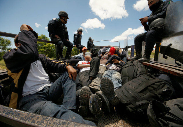 Riot police officers keep watch next to protesters from the National Coordination of Education Workers (CNTE) teachers’ union, who were detained after clashing with the police during a protest against President Enrique Pena Nieto's education reform, in the town of Nochixtlan, northwest of the state capital, Oaxaca City, Mexico June 19, 2016. REUTERS/Jorge Luis Plata FOR EDITORIAL USE ONLY. NO RESALES. NO ARCHIVES.